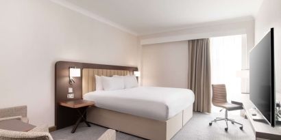 Day use room with work desk and chair, TV and sofa at the Hilton London Gatwick Airport.