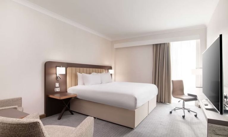 Day use room with work desk and chair, TV and sofa at the Hilton London Gatwick Airport.