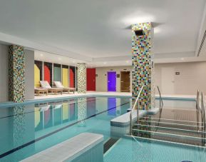 Refreshing indoor pool with lounge chairs at Hilton London Wembley.