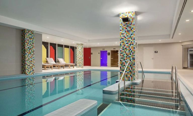 Refreshing indoor pool with lounge chairs at Hilton London Wembley.