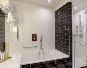 Guest bathroom with shower and tub at Hilton London Wembley.