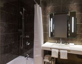 Guest bathroom with shower and tub at AC Hotel Cincinnati At Liberty Center.