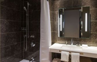 Guest bathroom with shower and tub at AC Hotel Cincinnati At Liberty Center.