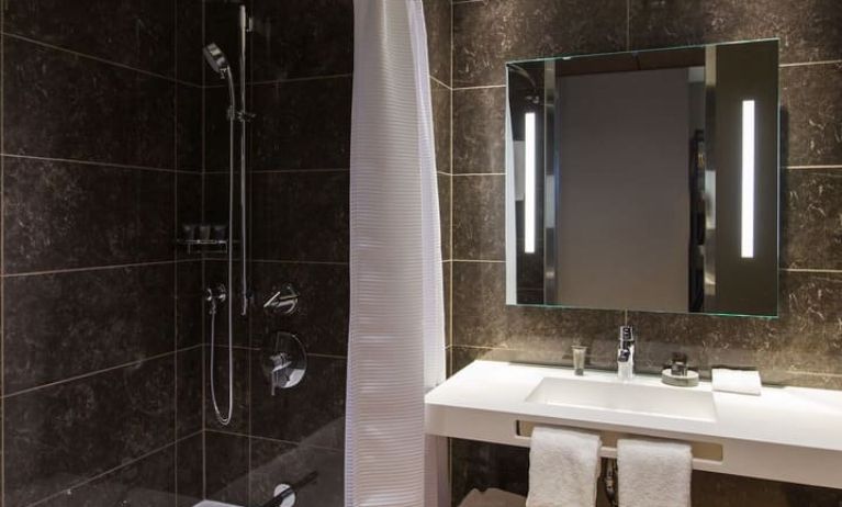 Guest bathroom with shower and tub at AC Hotel Cincinnati At Liberty Center.