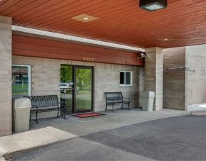 Outdoor seating and hotel entrance at Coratel Inn & Suites By Jasper River Falls.