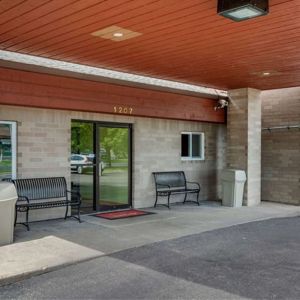 Outdoor seating and hotel entrance at Coratel Inn & Suites By Jasper River Falls.