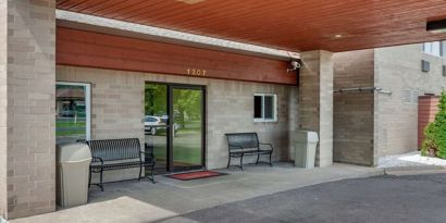 Outdoor seating and hotel entrance at Coratel Inn & Suites By Jasper River Falls.