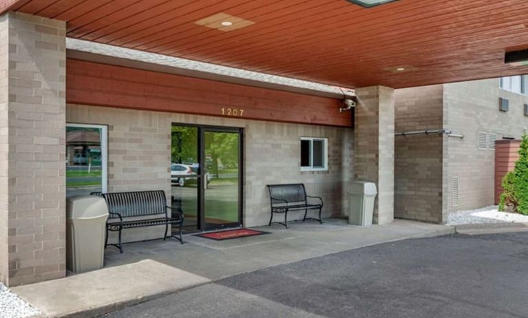 Outdoor seating and hotel entrance at Coratel Inn & Suites By Jasper River Falls.