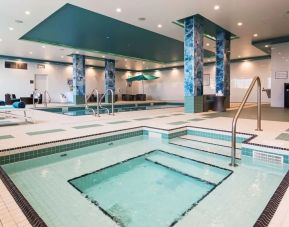 Relaxing indoor pool with jacuzzi and lounge chairs at Executive Residency By Best Western.