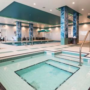 Relaxing indoor pool with jacuzzi and lounge chairs at Executive Residency By Best Western.