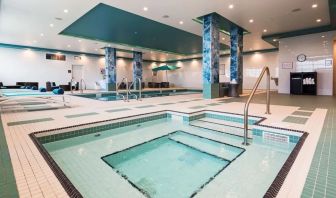 Relaxing indoor pool with jacuzzi and lounge chairs at Executive Residency By Best Western.