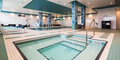 Relaxing indoor pool with jacuzzi and lounge chairs at Executive Residency By Best Western.