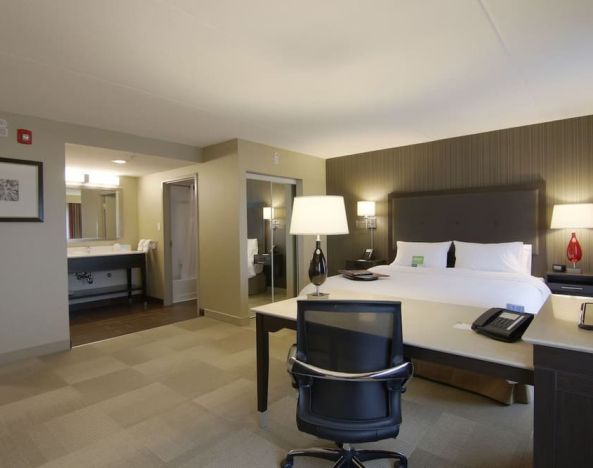 Day use room with king size bed, sofa, TV and working station at the Hampton Inn & Suites by Hilton Toronto Markham.