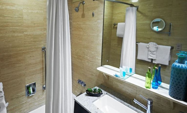 Guest bathroom with shower and tub at Miami International Airport Hotel.