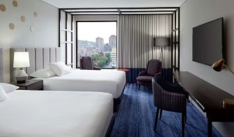 Twin day use room with work desk, lounge area and window view at DoubleTree By Hilton Montreal.