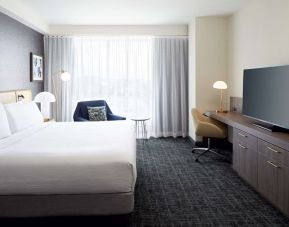 Day use room with king bed, TV, work desk and lounge area at Hilton Garden Inn Montreal Midtown.