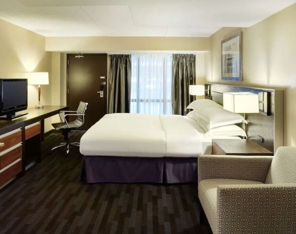 Day use room with TV, work desk, lounge area and private bathroom at Hilton Winnipeg Airport Suites.