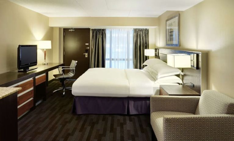 Day use room with TV, work desk, lounge area and private bathroom at Hilton Winnipeg Airport Suites.