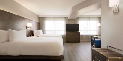 Day use twin room with TV screen, lounge area and work space at the Embassy Suites By Hilton Toronto Airport.