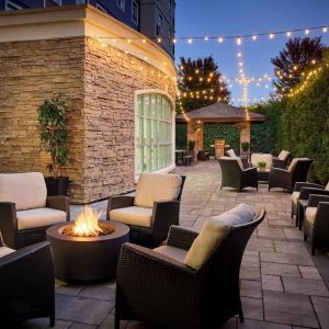 Outdoor patio with lounge seating and fireplace  at Staybridge Suites Oakville-Burlington.