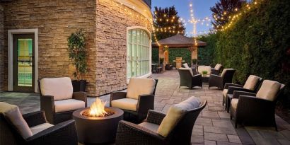 Outdoor patio with lounge seating and fireplace  at Staybridge Suites Oakville-Burlington.