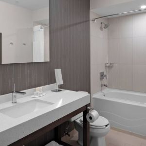 Private guest bathroom with tub and free toiletries at Courtyard By Marriott Edmonton Downtown.