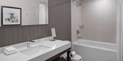 Private guest bathroom with tub and free toiletries at Courtyard By Marriott Edmonton Downtown.