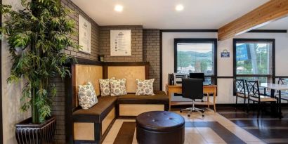 Hotel lobby with lounge area and workspace with computer and printer at Days Inn Vernon.