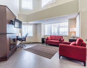 Lobby lounge area with fireplace and workspace with computer, printer and ergonomic chair at Comfort Inn Thetford Mines. 