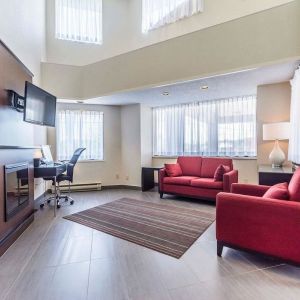 Lobby lounge area with fireplace and workspace with computer, printer and ergonomic chair at Comfort Inn Thetford Mines. 