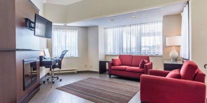 Lobby lounge area with fireplace and workspace with computer, printer and ergonomic chair at Comfort Inn Thetford Mines. 