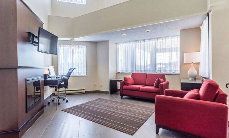 Lobby lounge area with fireplace and workspace with computer, printer and ergonomic chair at Comfort Inn Thetford Mines. 