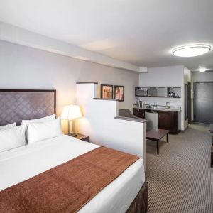 Day use studio suite with living area, workspace and in-room kitchen at Acclaim Hotel Calgary Airport.