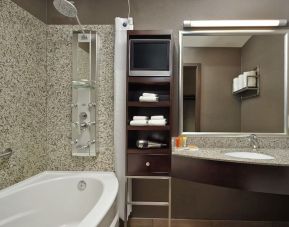 Private guest bathroom with tub, shower and free toiletries at Acclaim Hotel Calgary Airport.