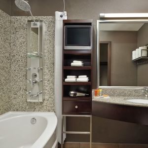 Private guest bathroom with tub, shower and free toiletries at Acclaim Hotel Calgary Airport.