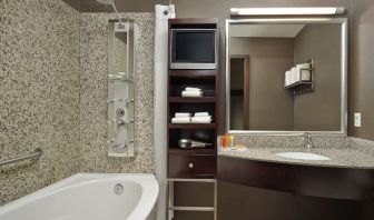 Private guest bathroom with tub, shower and free toiletries at Acclaim Hotel Calgary Airport.