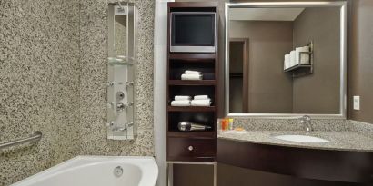 Private guest bathroom with tub, shower and free toiletries at Acclaim Hotel Calgary Airport.