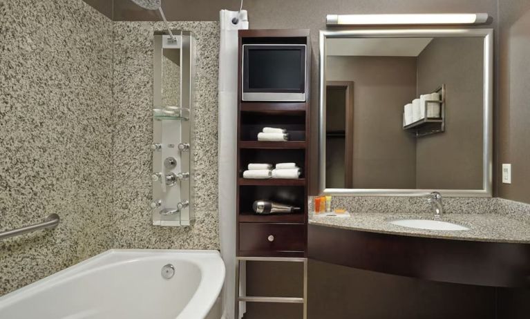 Private guest bathroom with tub, shower and free toiletries at Acclaim Hotel Calgary Airport.