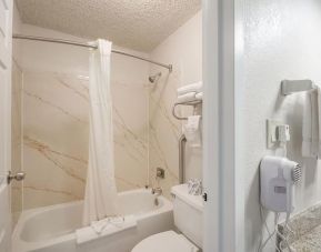 Guest bathroom with shower and tub at Coratel Plus Suites Wichita West Airport.