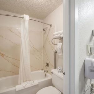 Guest bathroom with shower and tub at Coratel Plus Suites Wichita West Airport.