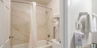 Guest bathroom with shower and tub at Coratel Plus Suites Wichita West Airport.