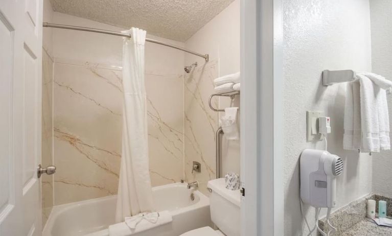 Guest bathroom with shower and tub at Coratel Plus Suites Wichita West Airport.