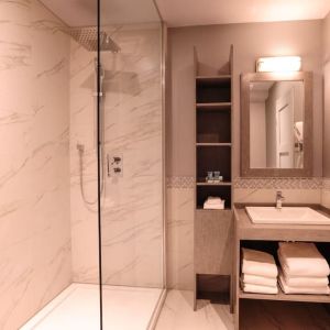 Guest bathroom with shower and free toiletries at Le Chabrol Hotel Et Suites.