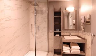 Guest bathroom with shower and free toiletries at Le Chabrol Hotel Et Suites.