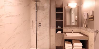 Guest bathroom with shower and free toiletries at Le Chabrol Hotel Et Suites.