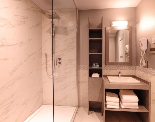 Guest bathroom with shower and free toiletries at Le Chabrol Hotel Et Suites.