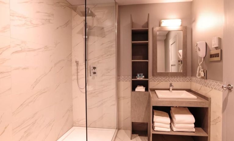 Guest bathroom with shower and free toiletries at Le Chabrol Hotel Et Suites.