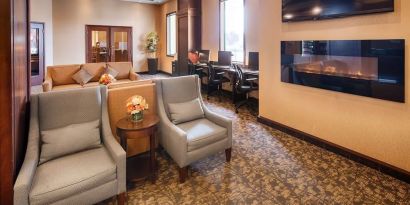 Comfortable lobby lounge with fireplace and workspace with computers, printer and ergonomic chairs at Best Western Plus Winnipeg Airport.