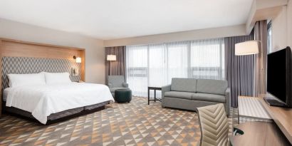 Bright and spacious king room with work desk and sofa at Holiday Inn Toronto Airport East.