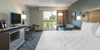 Day use room with TV, work desk, living area and balcony at Holiday Inn Kingston Waterfront.